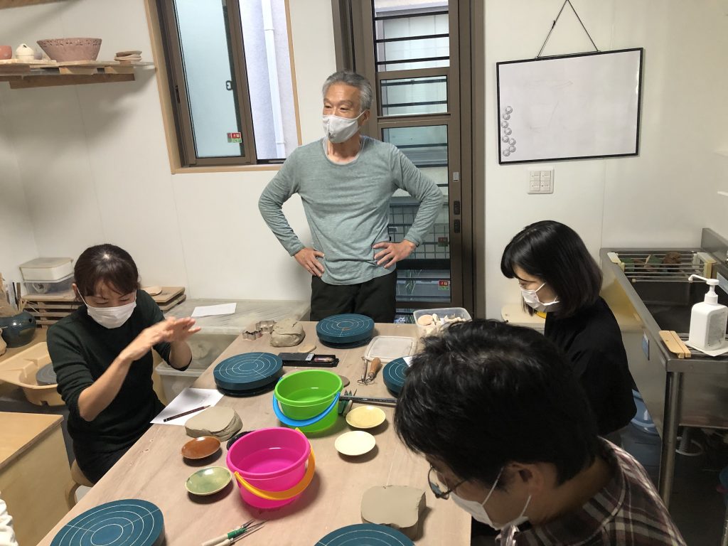 陶芸を先生が生徒に教えている。