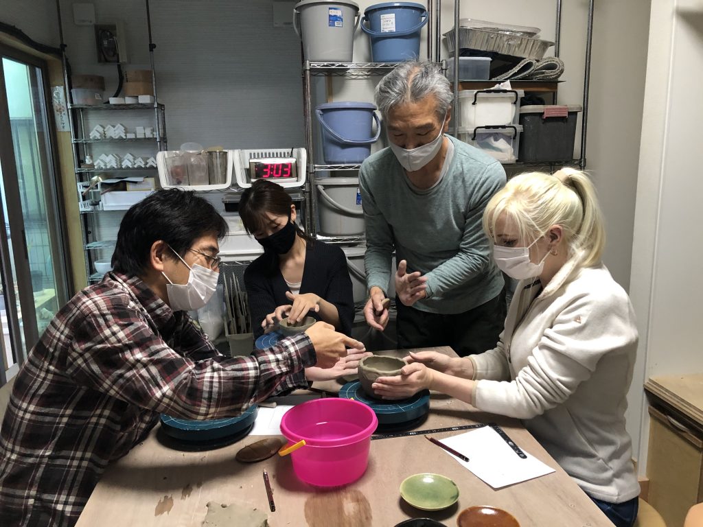 日本人が外国人に陶芸を教えている
