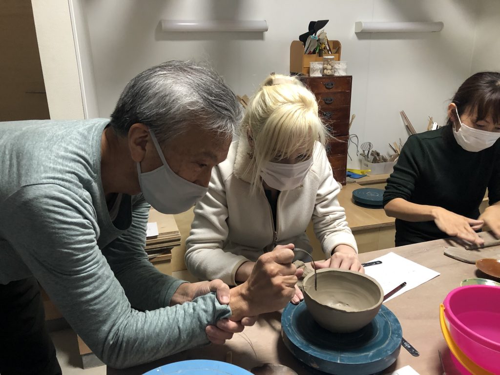 陶芸の先生が外国人に陶芸を教えている