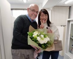 花束を持った外国人の先生と日本人生徒のリエさん