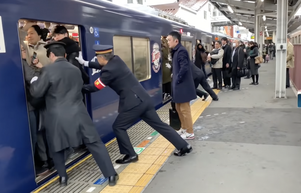 駅員が乗客を押している